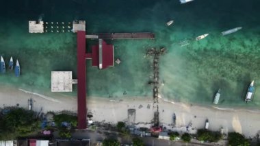 Nusa Ceningan Bali Endonezya 'daki Çapalı Oturan Teknelerle Kristal Berrak Mavi Sahil Suyu boyunca uçmak, sahil boyunca okyanusta yüzen tekneleri göstermek. Yelkenli bir teknenin havadan görünüşü