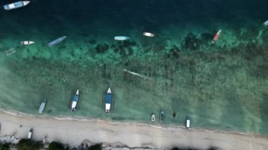 Nusa Ceningan Bali Endonezya 'daki Çapalı Oturan Teknelerle Kristal Berrak Mavi Sahil Suyu boyunca uçmak, sahil boyunca okyanusta yüzen tekneleri göstermek. Yelkenli bir teknenin havadan görünüşü