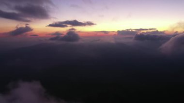 Gün batımından bir saat sonra bulutların ve tepelerin üzerinden alçak hava manzaralı bir uçuş. Akşam partisi konsepti ve gece uçuşları bulutlu arka plan. Gökyüzündeki güzel ay.. 