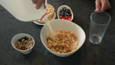 Beyaz kaseye müsli mısır gevreğiyle süt dökmek sağlıklı granola, vejetaryen diyeti, alerjiye dayanıklı enerji, sabah enerjisi, kilo verme konsepti, sütlü mısır gevreği, kuru gıda.