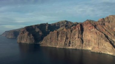 Sahil şeridinde kayalık kahverengi uçurumlar olan sakin bir okyanus manzarası. Los Gigantes Tenerife.Kanarya Adaları, okyanus dalgalarının üst hava manzarası kayaların arka planına, Tenerife 'ye, Kanarya Adalarına, İspanya' ya, Atlantik 'e çarpar. 