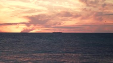 4K 'nin üzerinde kırmızı günbatımı. Güneş ufukta beliriyor. Kızıl gökyüzü, sarı güneş ve inanılmaz deniz. Yaz günbatımı deniz manzarası. Atlantik Okyanusu plaj günbatımı. Döner bulutların içindeki güneş olağanüstü doğal gün batımları, dramatik deniz gündoğumu. Yanan gökyüzü ve parlayan