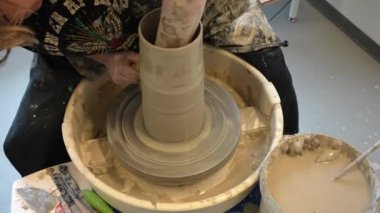 Çömlekçi çarkında çalışan elleri kapatın. Potter çömlekçi çarkındaki çömlek aletleriyle, üst görünüm, el işi fabrikası özgünlüğüyle killi ürünü şekillendiriyor. Potter iş başında, kapat. El yapımı, el yapımı. Eller çömlekçi çarkında dönen çömlek kalıbı. 
