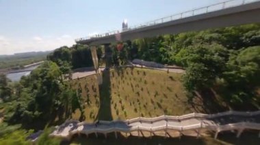  FPV drone, Reunion Arch, Kyiv: Halkın Dostluk Kemeri ve Volodymyr Hill Köprüsü. Kiev 'deki parkın ve yaya köprüsünün manzarası. Parktaki insanlar ve yeşil ağaçlar. Drone Video. Ukrayna. Avrupa