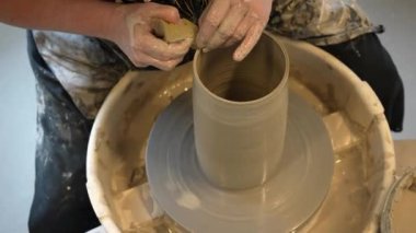 Çömlekçi çarkında çalışan elleri kapatın. Potter çömlekçi çarkındaki çömlek aletleriyle, üst görünüm, el işi fabrikası özgünlüğüyle killi ürünü şekillendiriyor. Potter iş başında, kapat. El yapımı, el yapımı..