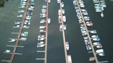 Tekne ve yat manzarası, yat parkı, yatlar, sürat tekneleri ve tekneler için otoparkı olan güzel bir koy. Yaz. Yatın sinematik hava görüntüsü, güzel körfezdeki iskeleye park etmiş birçok yelkenlinin dikey hava görüntüsü.
