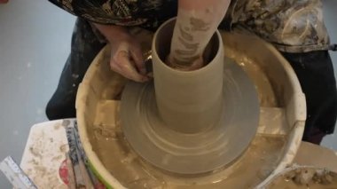 Çömlekçi çarkında çalışan elleri kapatın. Potter çömlekçi çarkındaki çömlek aletleriyle, üst görünüm, el işi fabrikası özgünlüğüyle killi ürünü şekillendiriyor. Potter iş başında, kapat. El yapımı, el yapımı. Eller çömlekçi çarkında dönen çömlek kalıbı. 
