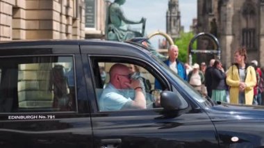 Edinburgh, İskoçya - Edinburgh 'un ortaçağ sokaklarında İngiliz taksisi. İngiliz taksi şoförü, İngiliz İngiltere ve İngiltere 'nin ulusal sembolü olan siyah taksici. Edinburgh 'un ortaçağ sokaklarında İngiliz taksisi. İngilizler 