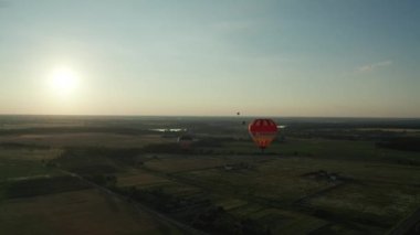 Balonlar gökyüzünde yüzüyor, Balon Festivali. Şişirilmiş büyük balon. Birkaç balon yerde yatıyor, şişiyor, ağaçların üzerinde uçan sıcak hava balonunun havadan görünüşü, renkli balon festivali. Sıcak Hava Balonu Festivali, Uçan renkli balonlar 