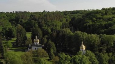 Yaz zamanı doğa panoramik manzara, kilisenin önündeki dağ, hava aracı görüntüleri. Güneşli bir günde göl kenarındaki eski kilise havadan kan gölüne döndü. Etrafında mavi su ve orman olan güzel bir manzara, Göl kenarındaki eski kilise güneşli bir günde gökyüzünden kanadı.