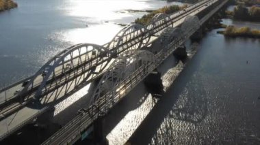 Bir köprünün insansız hava aracı videosu. Kiev 'deki modern otomobil ve eski demiryolu köprüleri. Kyiv, Ukrayna. Dnipro nehrinin üzerinde dramatik renkli gün batımı. Ukrayna 'nın tarihi manzarası. Güzel manzaralı 