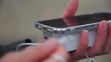Cep telefonunu güneş enerjisi bankasına bağlayan eller, cep telefonunu güneş enerjisi bankasına bağlayan eller. Powerbank 'i Smartphone' a, Smartphone 'u dış bataryanın şarj edilmesine, akıllı telefonu elektrik bankasıyla şarj eden kadına bağla. 