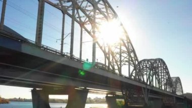 Bir köprünün insansız hava aracı videosu. Kiev 'deki modern otomobil ve eski demiryolu köprüleri. Kyiv, Ukrayna. Dnipro nehrinin üzerinde dramatik renkli gün batımı. Ukrayna 'nın tarihi manzarası. Güzel manzara, bir köprünün insansız hava aracı videosu. Kiev hava manzaralı gün batımı