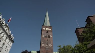 Aarhus Danimarka şehir merkezindeki kilise güneşli bir günde, Aarhus Danimarka Şehir Merkezi yazın güneşli bir günde çok sayıda yayayla, şehrin mimarisi, Aarhus Katedrali, alışveriş caddesi merkezinin kilise manzarası çatıdan satış yapıyor.