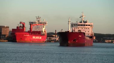 Yükü boşaltmak için bir konteynır limana giriyor, boşaltmak için bir konteynır gemisi limana giriyor. Büyük konteynır gemisi sanayi limanına giriyor, kırmızı renkli ultra büyük boş konteynır gemisi denizde, yukarıdan aşağıya bakıyor. Kargo gemisi giriyor. 