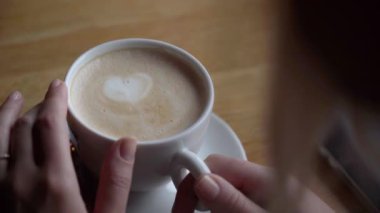 Köpüklü beyaz kapuçino. Kaşık karıştırılmış cappuccino. Köpük Kalpli Kahve Latte 'nin yakın çekimi. Barista 'nın güzel kompozisyonu masaya bir kapuçino koyar, beyaz şeker. 