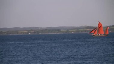 Danimarka 'da Tekne Festivali Aarhus, İskandinavya, Modern yelken yatı eski geleneksel İskandinav limanına giriyor, antik Viking gemisinin direği aşağı doğru yelken açıyor yaz yelkenli yarışları sırasında yatları kapatıyor