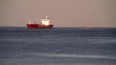 Bir konteynır kargo gemisi boşaltmak için limana giriyor. Büyük konteynır gemisi sanayi limanına giriyor, kırmızı renkli ultra büyük boş konteynır gemisi denizde, yukarıdan aşağıya bakıyor. Kargo gemisi limana giriyor.