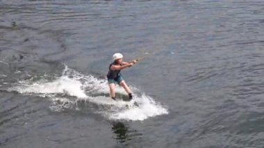 Aarhus, Danimarka - 05.21.2023, Çocuk uyanma parkındaki gölette kablo wakeboard ile meşgul. Beyaz bir gencin gölde wakeboard 'da numaralar yaptığı görüntüler, Wakeboard kullanan bir adam.