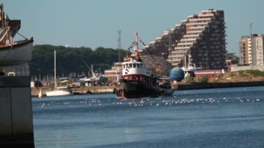 Danimarka 'da Tekne Festivali Aarhus, İskandinavya, Modern yelken yatı eski geleneksel İskandinav limanına giriyor, antik Viking gemisinin direği aşağı doğru yelken açıyor yaz yelkenli yarışları sırasında yatları kapatıyor