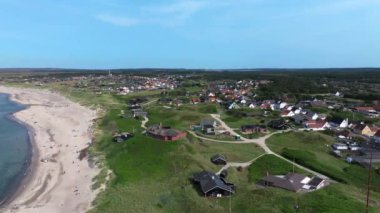 Danimarka 'nın yeşil arazisinde, köydeki evlerin havadan çekilmiş görüntüleri, deniz kenarında lüks evler ve deniz kenarında renkli evleri olan geleneksel İskandinav köyü yolu.