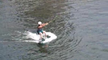 Aarhus, Danimarka - 05.21.2023, Çocuk uyanma parkındaki gölette kablo wakeboard ile meşgul. Beyaz bir gencin gölde wakeboard 'da numaralar yaptığı görüntüler, Wakeboard kullanan bir adam.