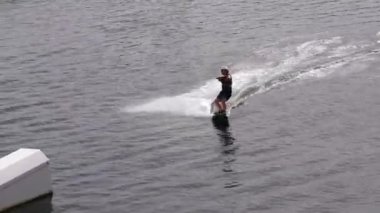Wakeboardcu parktaki kablo TV 'de, açık havada suyla aşırı ilgilenen, suda sörf yapan, nehirde wakeboard kullanan genç bir adam., 