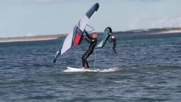 近代的なウォータースポーツ 翼と風の力を利用して海に水車に乗る カイトサーフィンに最適な場所 フィットアスリートのビデオは ハイドロフォイルウィングサーフィンを練習します — ストック動画