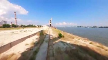 FPV, İHA 'dan inşaat vinci görünüyor. Arkaplan şehir manzarasına karşı inşaat vinçleri ve bulutlu gökyüzü, arkaplan şehir manzarasına karşı inşaat vinçleri ve bulutlu gökyüzü