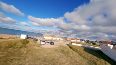 FPV, Klitmoller Yumuşak Dalgalar Sihirli Kumsalda, Muhteşem Mavi Su, Danimarka, Avrupa, panoramik kum tepeleri, plaj, ve dalgalı Kuzey Denizi, Emerald deniz rengi, kayalara çarpan dalgalar 