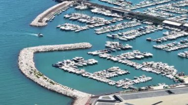 Akdeniz 'de yelkenli ve yatların hava görüntüsü. Uzakta hareket eden çok sayıda tekne gemisi var. Arka planda dağlar. Sakin mavi su. Güneşli bir yaz günü. İtalya. 