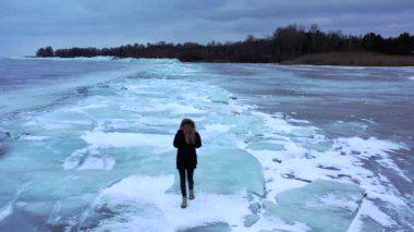 Göl, donmuş gölde yürüyen kız donmuş bir gölün buzunda yürüyen kız, İzlanda 'da elmas plajı boyunca yürüyen kadın. Ayaklar buzda, kız donmuş gölde yürüyor. 