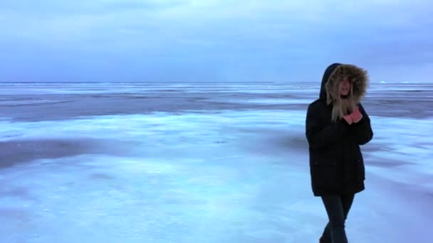 凍った湖を歩く少女 凍った湖バイカル湖のひび割れた氷を歩き アイスランドのダイヤモンドビーチを歩いている女性 氷の上のフィート 凍った湖を歩く少女 — ストック動画
