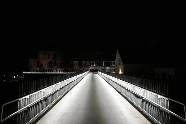 Modern lit pedestrian bridge, Illuminated Modern City Against Clear Sky At Night , people walking on a pedestrian bridge