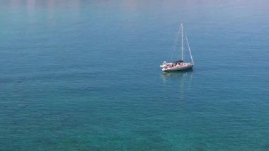 Güzel bir yatın havadan görünüşü. Yazın gün batımında denizde tekne gezisi. Ada, Yunanistan. Lüks yatlar, yelkenliler, temiz mavi sular, gökyüzü, dağ manzarası. Seyahat et. Seyahat tatili, mavi deniz lagünü. 