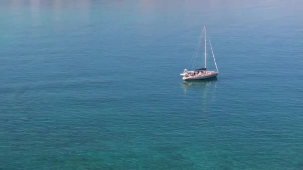 美しいヨットの空中ビュー 夏の夕日には海でボートをする ギリシャ 高級ヨット 澄んだ青い水 山のトップビュー トラベル クルーズバケーション ブルーシーラグーン — ストック動画