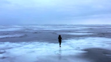 Göl, donmuş gölde yürüyen kız donmuş bir gölün buzunda yürüyen kız, İzlanda 'da elmas plajı boyunca yürüyen kadın. Ayaklar buzda, kız donmuş gölde yürüyor. 