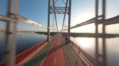 FPV, Kyiv şehrindeki yaya köprüsü. Dnipro nehri üzerinde köprü, altın saat, insansız hava aracı görüntüsü Kyiv yaya köprüsü, Truchaniv adası ve Dinyeper nehri güzel güneşli bir günde. Ukrayna 'nın başkenti