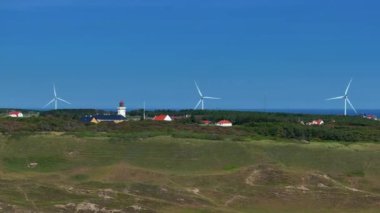 Gün batımında bir rüzgar çiftliğinin drone görüntüsü. Çoklu rüzgar türbinleri, güzel güneşli yaz sonbahar karasularında rüzgar türbinleri. Dağdan geçen kıvrımlı bir yol. Yeşil ekolojik enerji üretimi.