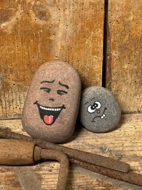 Mutsuz yüzlerin taşlarının arka planına karşı küçük bir taşın üzerine el boyaması mutlu yüz.