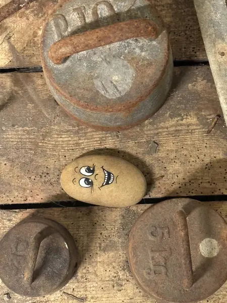 hand painted happy face on a small stone against the background of stones of unhappy faces