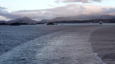 Norveç 'te gezinti. Bottan fiyordun manzarası, tekneden dağların manzarası, şelaleler, yolcu gemileri ve hassas tekneler turistleri gemiden kıyıya taşıyan mavi gökyüzü ile güzel bir günde