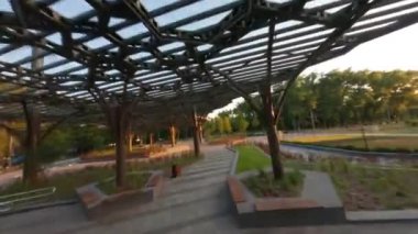 Kyiv şehrindeki Sonsuz Zafer Parkı. Hava güzel, FPV insansız hava aracı yolda uçuyor, Kiev, Ukrayna, Park Köprüsü Mariinsky Parkı Kiev Ukrayna 'nın yeşil çim tepesi 