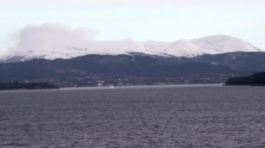 Norveç 'te gezinti. Bottan fiyordun manzarası, tekneden dağların manzarası, şelaleler, yolcu gemileri ve hassas tekneler turistleri gemiden kıyıya taşıyan mavi gökyüzü ile güzel bir günde