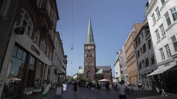 在一个繁忙的日子里 奥胡斯丹麦市中心 在一个阳光明媚的夏日 与许多行人在一起 城市的建筑 奥胡斯大教堂 购物街中心从摇摇欲坠的屋顶上俯瞰 — 图库视频影像