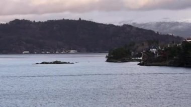 Norveç 'te gezinti. Bottan fiyordun manzarası, tekneden dağların manzarası, şelaleler, yolcu gemileri ve hassas tekneler turistleri gemiden kıyıya taşıyan mavi gökyüzü ile güzel bir günde