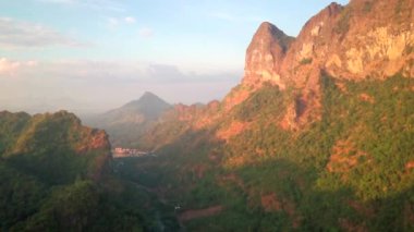 Hava aracı videosu, gün batımında Vietnam 'ın dağları ve pirinç tarlaları. Bereketli yeşil yağmur ormanları şafak vakti sisli dağlarla kaplı Karst Dağları Kedi Ba Adası, Halong Körfezi, Vietnam