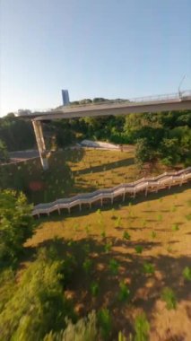 FPV drone, Reunion Arch, Kyiv: Halkın Dostluk Kemeri ve Volodymyr Hill Köprüsü. Kiev 'deki parkın ve yaya köprüsünün manzarası. Parktaki insanlar ve yeşil ağaçlar. Drone Video. Ukrayna. Avrupa