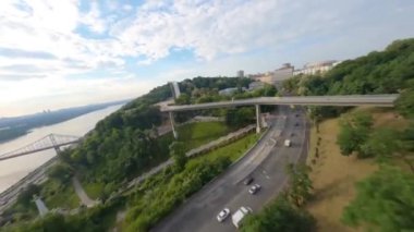 KIEV, Ukrayna - 19 Nisan 2021: FPV drone, Reunion Arch, Kyiv: Halkların Dostluk Kemeri ve Volodymyr Tepesi köprüsü. Kiev 'deki parkın ve yaya köprüsünün manzarası. Parktaki insanlar ve yeşil ağaçlar. 