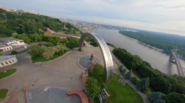 KIEV, Ukrayna - 19 Nisan 2021: FPV drone, Reunion Arch, Kyiv: Halkların Dostluk Kemeri ve Volodymyr Tepesi köprüsü. Kiev 'deki parkın ve yaya köprüsünün manzarası. Parktaki insanlar ve yeşil ağaçlar. 